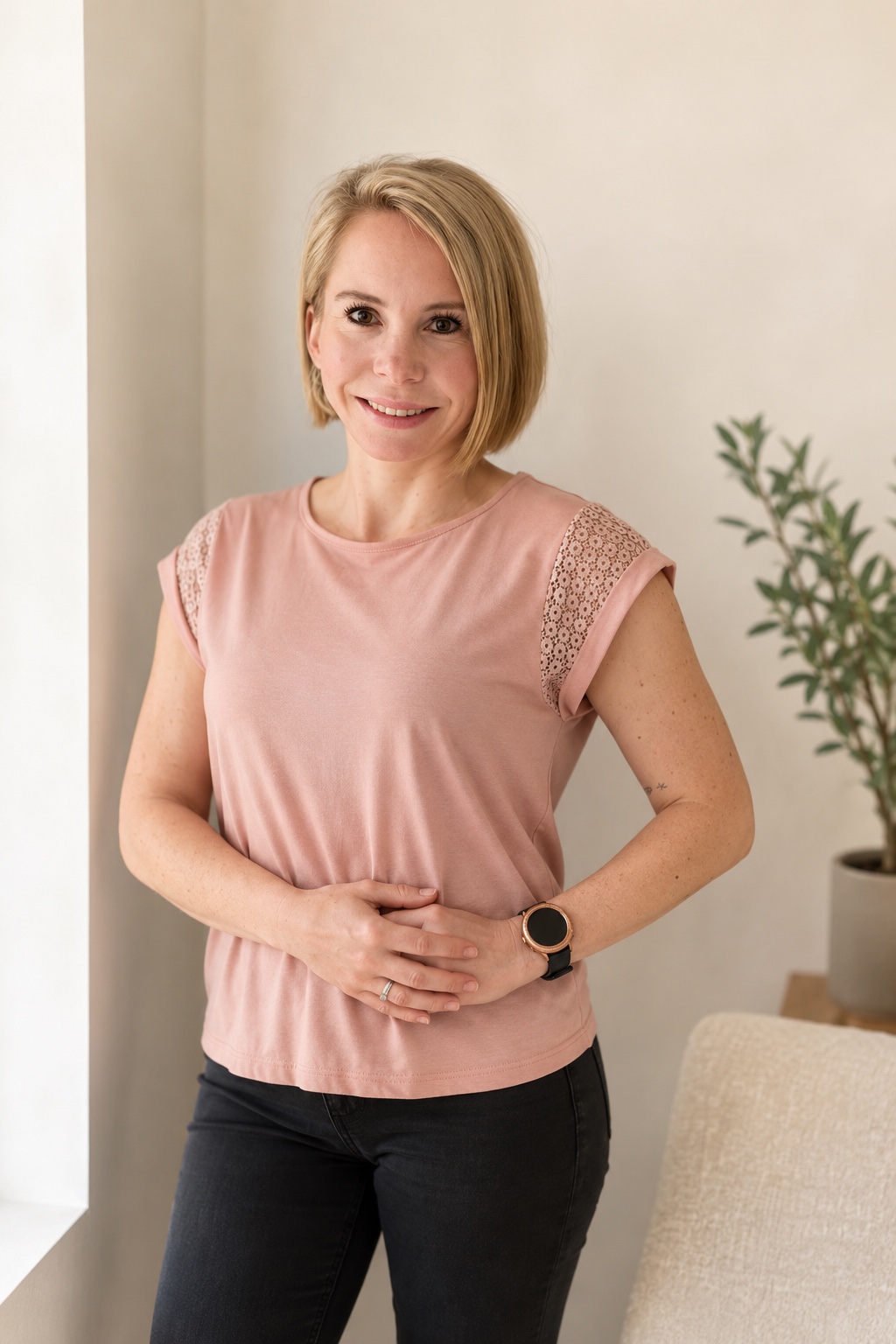 Annika steht in einem hellen Raum und legt die Hände ruhig auf ihre Körpermitte.